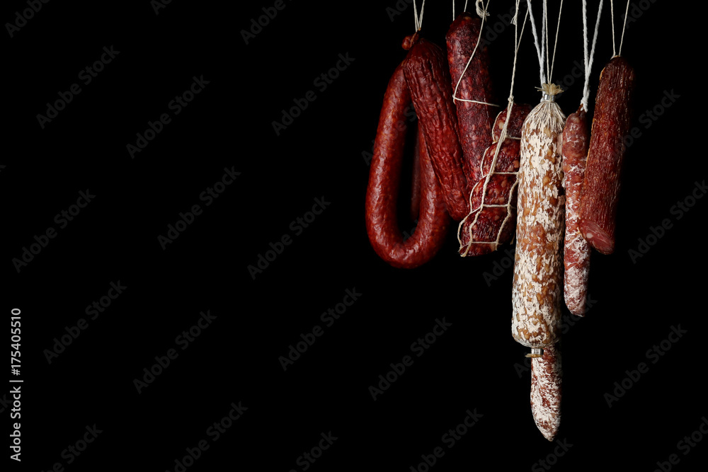 Wall mural Delicious sausages hanging on dark background