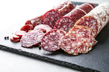 Delicious sliced sausages on slate plate