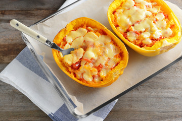 Baking dish with halves of stuffed spaghetti squash on table