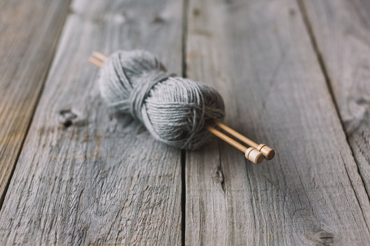 Grey ball of wool with bamboo needles on rustic wood table