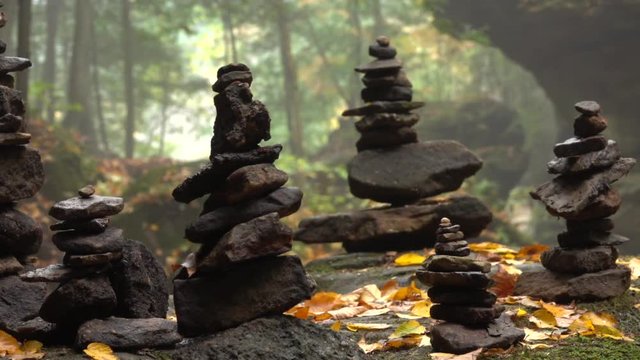 CLOSE UP DOF: Stone sculpture on mossy rock left by travelers as a spiritual memento. Pile of stacked stones in gorgeous Hocking Hills State Park, Ohio, America. Rocky sculptures in foggy autumn woods