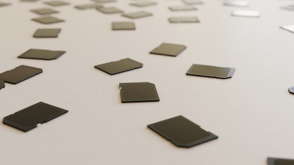 black SD cards scattered on a white surface with shallow depth of field