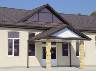 building with a brown roof. The main entrance to the house. Modern materials of finish and roofing
