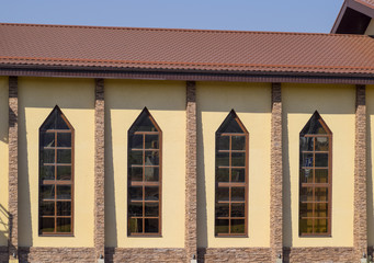 building with yellow walls and a red-brown roof. Modern materials of finish and roofing