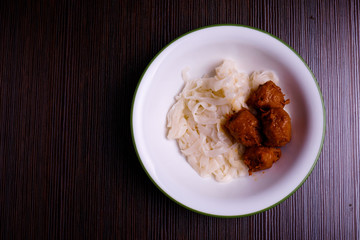 Kuey teow and meatballs  in a white bowl on the table