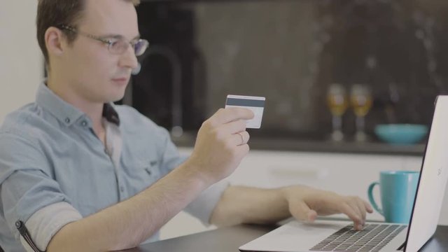 man suit inserting credit card number on laptop