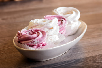  pink and white marshmallows (zephyr) on a gray wooden background.