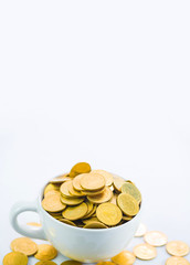 Golden coins in white cup of coffee on the white background.