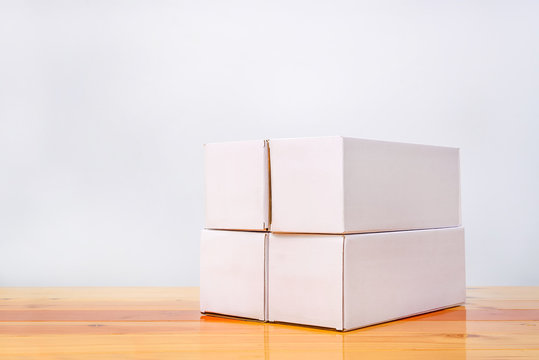Empty four Package white cardboard box for long items on wooden table with copy space.