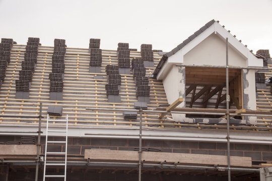 working on the roof sheeting and outriggers or ladder of a new, two story, commercial apartment building