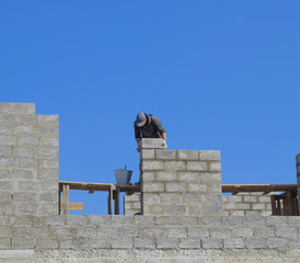 The builder builds the wall of the house from the cinder block. Worker at the construction site