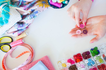 Female hands and accessories for sewing. Buttons, fabric and thread.