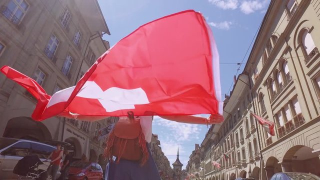 BERN, BERN-MITTELLAND /SWITZERLAND – 28 JUNE 2016: Tourist Woman Walks with a Swiss Flag on Kramgasse on 28 June in Bern, Switzerland. The Kramgasse is part of the UNESCO Cultural World Heritage Site.