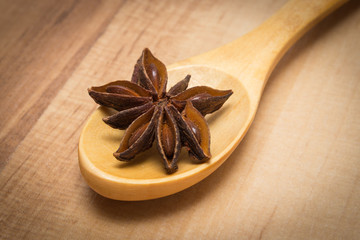 Star anise with wooden spoon on wooden board, seasoning for cooking or baking