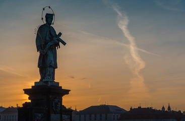 Fototapeta premium Sculpture on Charles bridge with sunrise in background