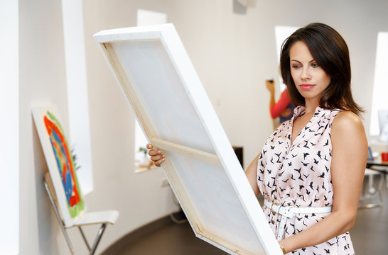 Young caucasian woman standing in art gallery front of  paintings