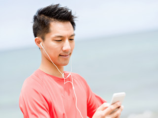 Sporty man with earphones on the sea coast