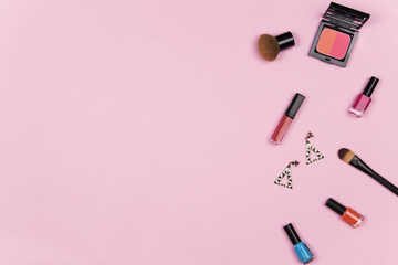 Obraz na płótnie Canvas Beauty blog fashion concept. Female pink styled : cosmetics, lipstick, nail polish, brush on, earring on pink background. Flat lay, top view trendy feminine background.