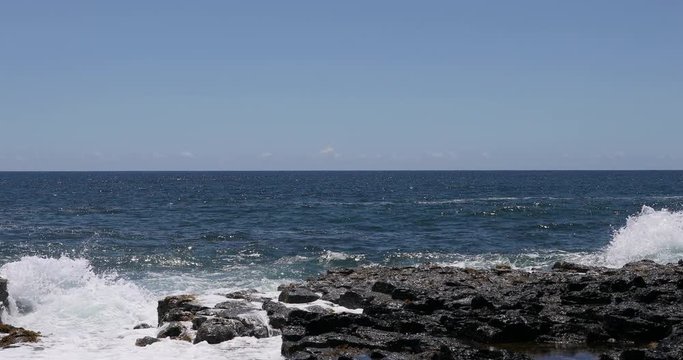 Beautiful violent waves crash rocky shore Kauai Hawaii. Economy is tourism based water, tropical beach recreation and fun. Beautiful clear blue ocean sea. Tourist enjoy tropical climate.