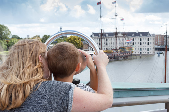 Mother and son looking through a telescope watching the city from the top.