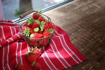 Metal basket with ripe strawberries on windowsill
