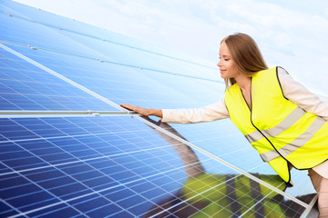 Beautiful young engineer standing near solar panels outdoors