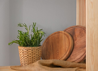 Wooden boards and pot with rosemary on shelf in kitchen