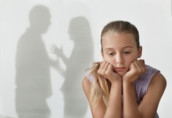 Little girl and silhouettes of quarreling parents on background. Domestic violence concept