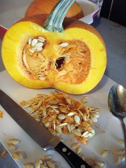 Half of Orange Pumpkin With Seeds, Knife and Spoon on Vintage White Cutting Board