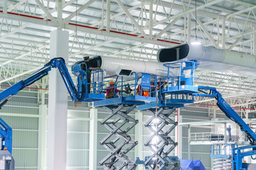 builder repairman install HVAC duct cleaning and ventilation pipes hanging from the ceiling inside new building.