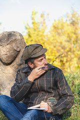 learned historian sits before stone sculpture on mound