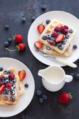 Belgian waffles with fresh berries on white plate.