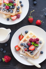 Belgium waffles with fresh berries on white plate. Top view