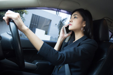 Fototapeta na wymiar Asian Woman Looking Smartphone while Driving Car to go to Work, Woman working Concept.