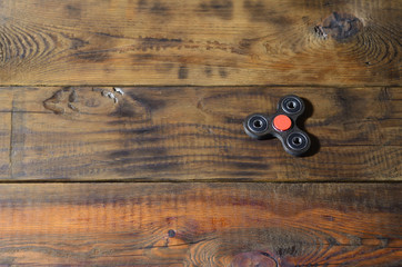 A rare handmade wooden fidget spinner lies on a brown wooden background surface. Trendy stress...