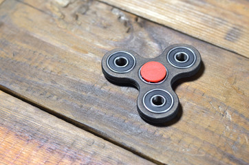 A rare handmade wooden fidget spinner lies on a brown wooden background surface. Trendy stress...