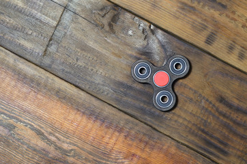 A rare handmade wooden fidget spinner lies on a brown wooden background surface. Trendy stress...