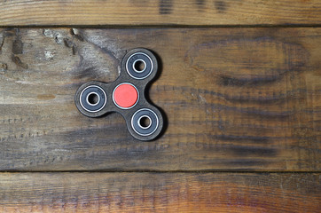 A rare handmade wooden fidget spinner lies on a brown wooden background surface. Trendy stress...
