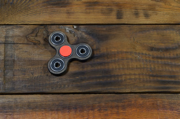 A rare handmade wooden fidget spinner lies on a brown wooden background surface. Trendy stress...