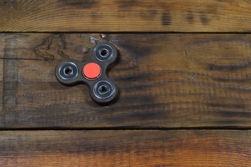 A rare handmade wooden fidget spinner lies on a brown wooden background surface. Trendy stress...