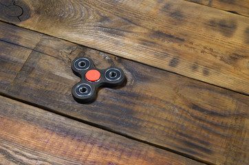 A rare handmade wooden fidget spinner lies on a brown wooden background surface. Trendy stress...