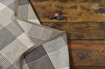 A rare wooden handmade spinner lies on a checkered plaid on a brown wooden background surface....