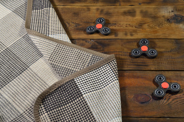 A rare wooden handmade spinners lies on a checkered plaid on a brown wooden background surface....