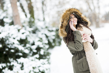 Young woman using phone in park at  cold winter day