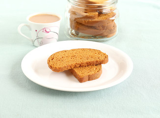 Fototapeta na wymiar Rusk, a popular, crunchy and crispy biscuit, and tea, on a plate.