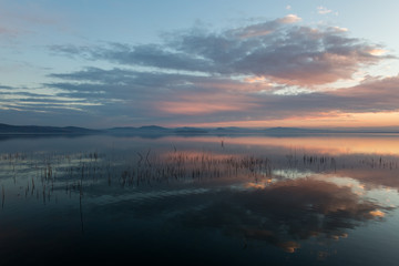 Perfect and symmetric clouds reflections on a lake at sunset, with warm and soft tones