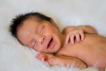 Fototapeta na wymiar Newborn baby boy smiling while sleeping