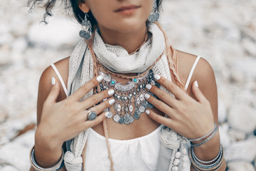 close up of boho styled woman on tropical beach with white pebble