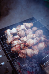 Grilled kebab cooking on metal skewers (grill). Roasted meat cooked at barbecue with smoke. Close up BBQ fresh pork meat chop slices. Traditional eastern dish, shish kebab.