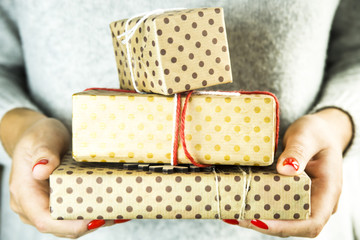 Christmas gifts packed in kraft paper in polka dots in female hands with red manicure